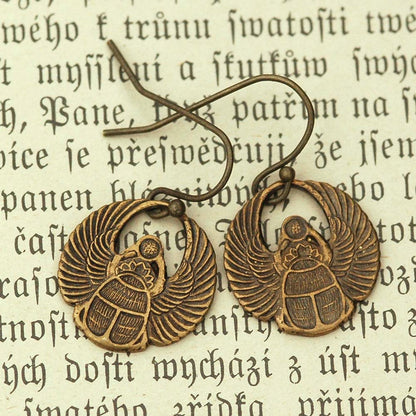 A pair of brass scarab earrings with Art Deco style patterns.