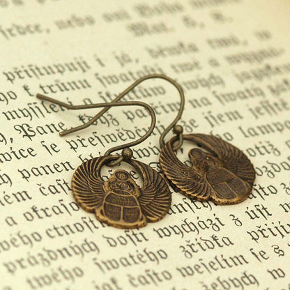 A pair of brass scarab earrings with Art Deco style patterns.