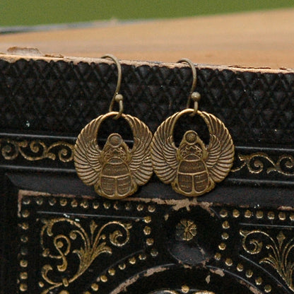 A pair of brass scarab earrings with Art Deco style patterns.