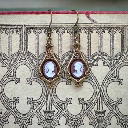 Antiqued brass earrings with purple and white cameos of women on filigree drop settings.