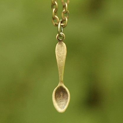 Brass spoon-shaped pendant on a necklace chain.