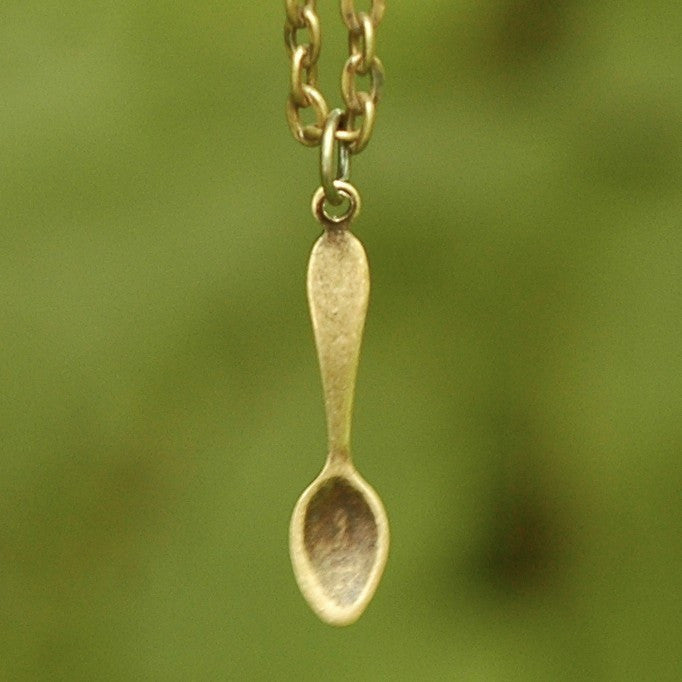 Brass spoon-shaped pendant on a necklace chain.