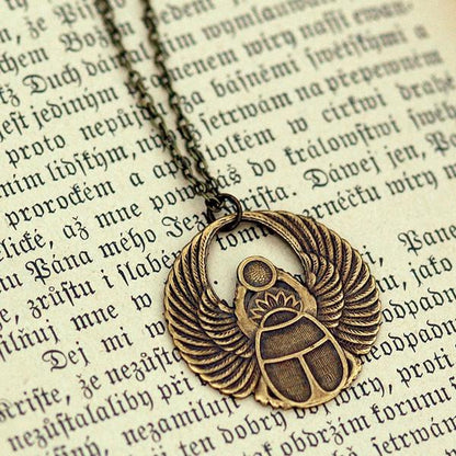 Antiqued brass scarab beetle pendant on a simple chain. Pendant is in a circular Art Deco design.