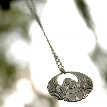 Antiqued silver scarab beetle pendant on a simple chain. Pendant is in a circular Art Deco design.