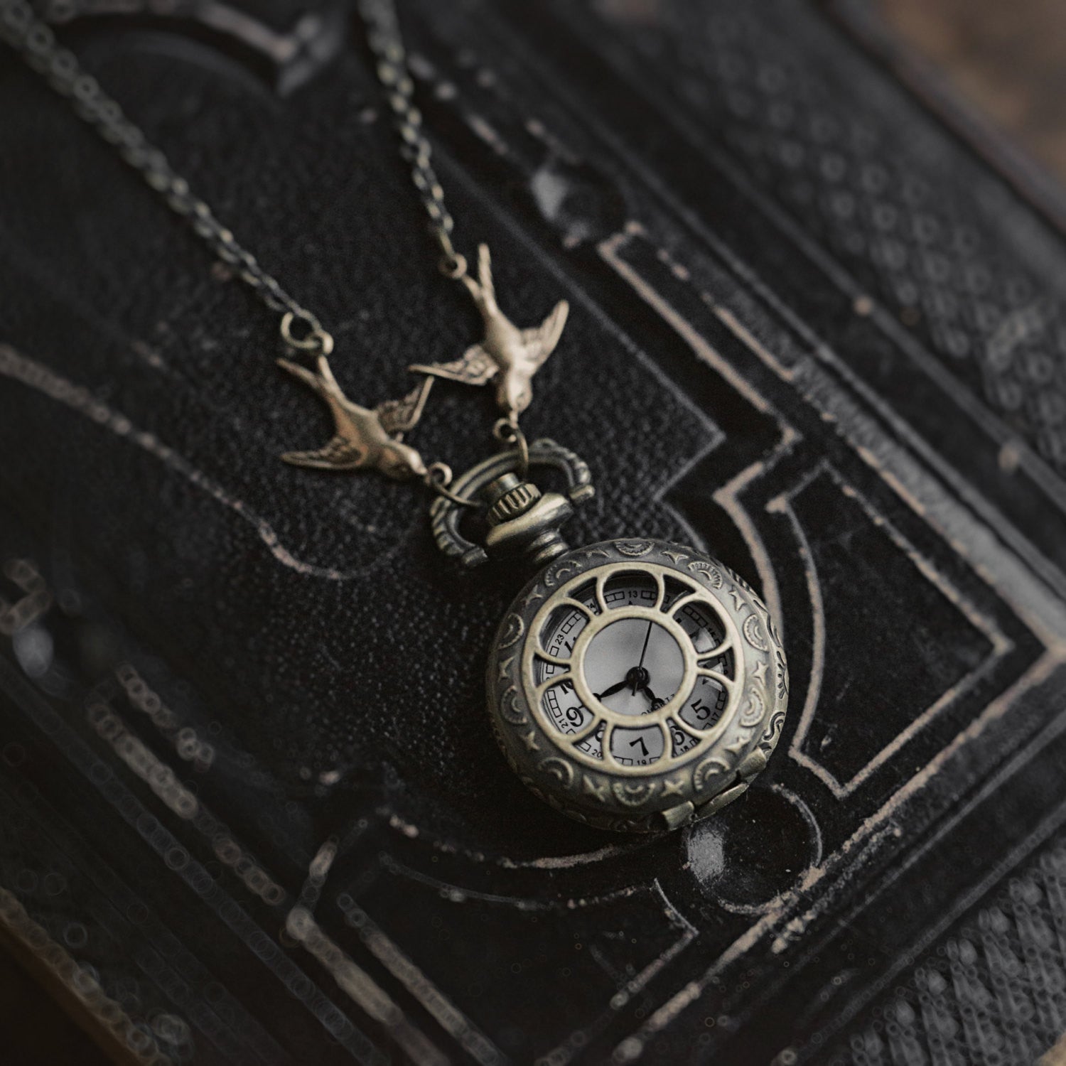 Antiqued brass pocket watch with a Daisy Window design. This watch is attached to birds connected to a brass chain.