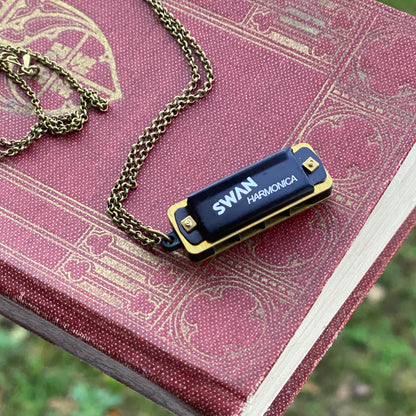 Miniature black SWAN harmonica on a brass chain.