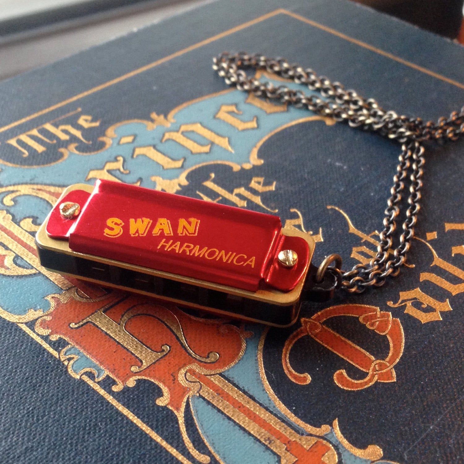 Miniature black SWAN harmonica on a brass chain.