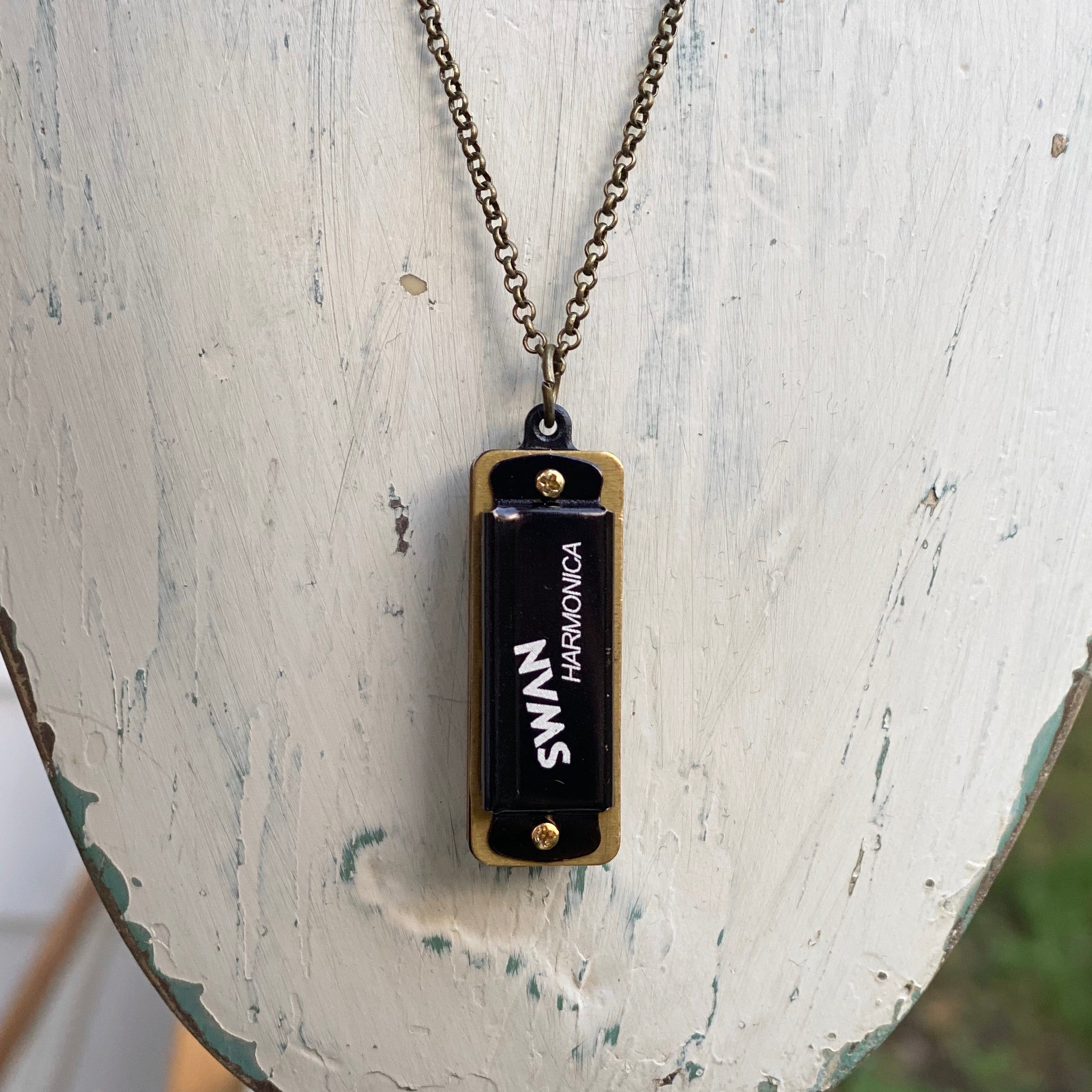 Miniature black SWAN harmonica on a brass chain.