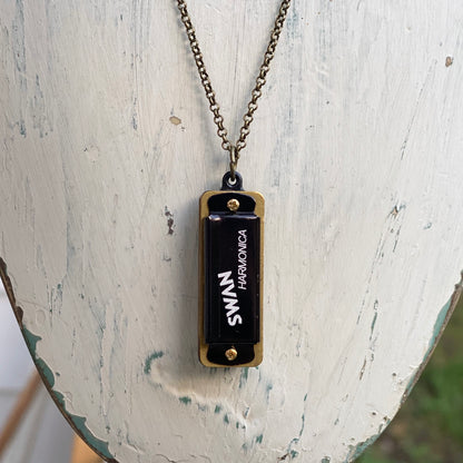Miniature black SWAN harmonica on a brass chain.