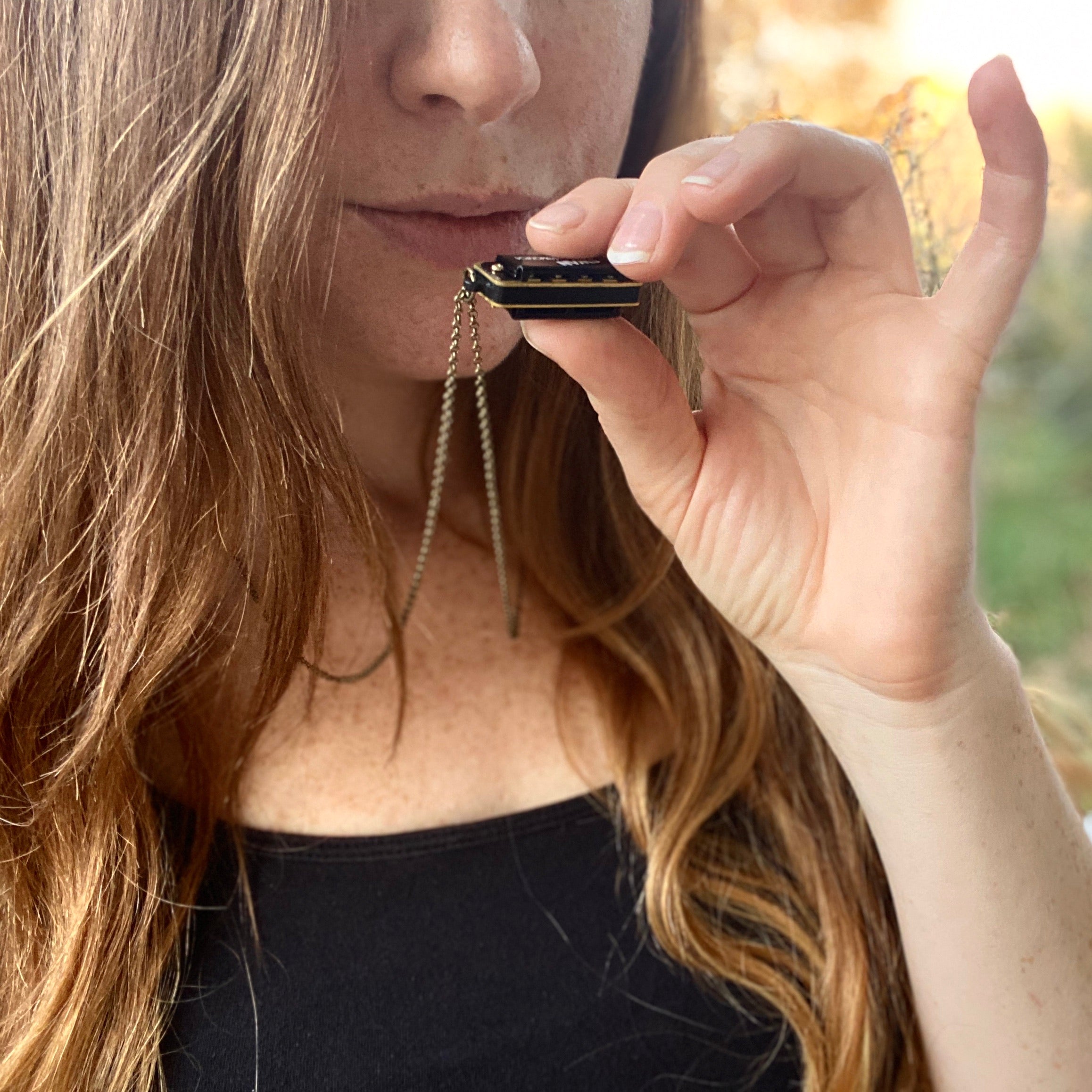 Miniature black SWAN harmonica on a brass chain.