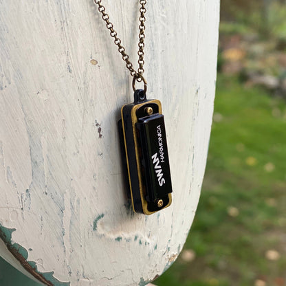 Miniature black SWAN harmonica on a brass chain.
