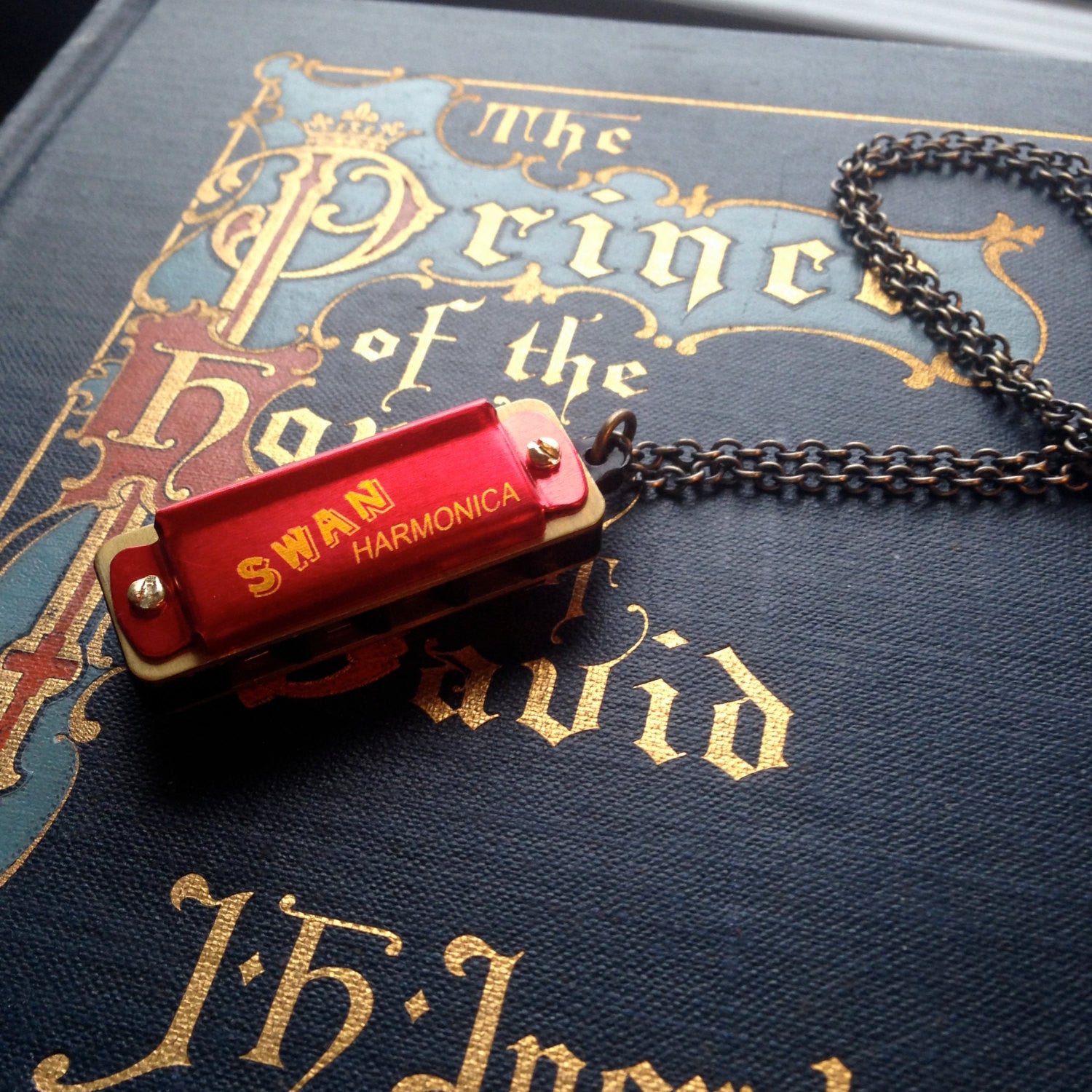 Miniature red SWAN harmonica on a brass chain.