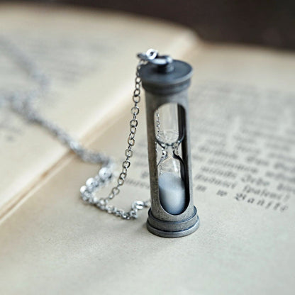 A functional hourglass in an antiqued silver frame hanging from a silver chain.