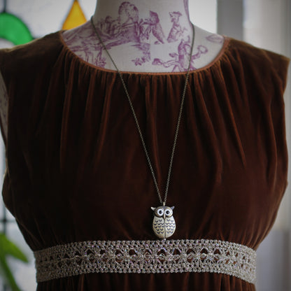 A bronze owl-shaped watch necklace with a quartz face. This watch is displayed on a display bust.