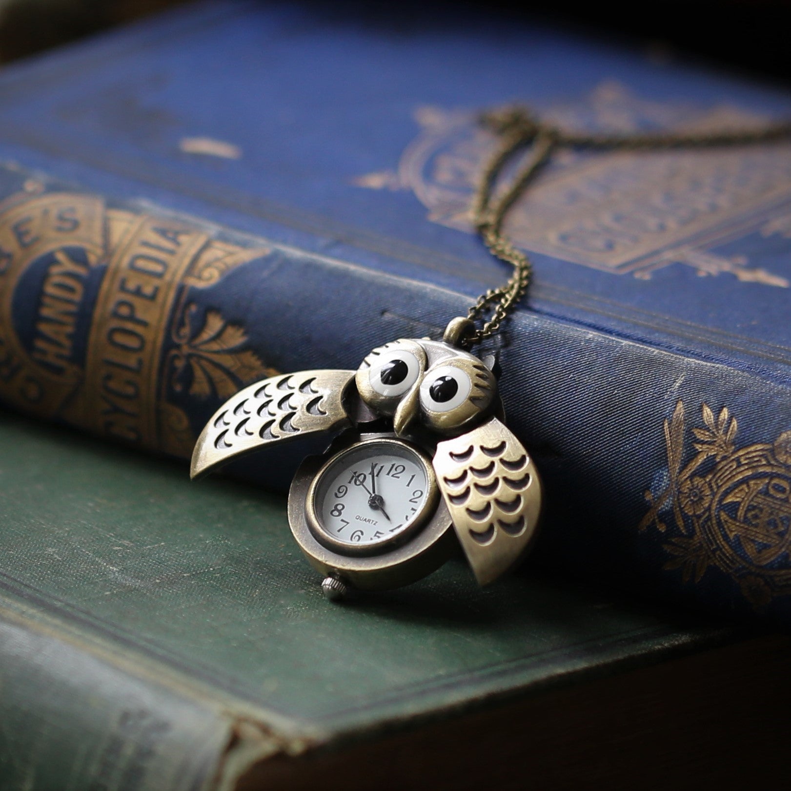 A bronze owl-shaped watch necklace with a quartz face. This watch is displayed open, with the owl's wings open to show the watch face.
