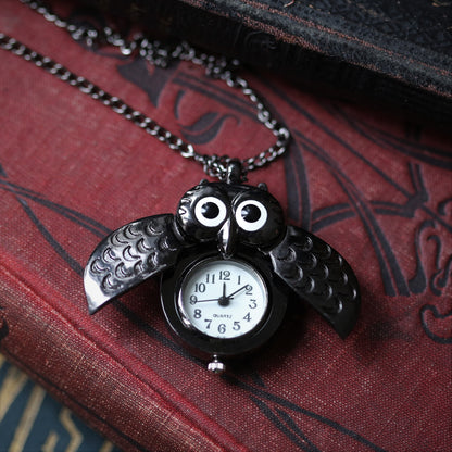 A gun metal owl-shaped watch necklace with a quartz face. This watch is displayed open, with the owl's wings open to show the watch face.