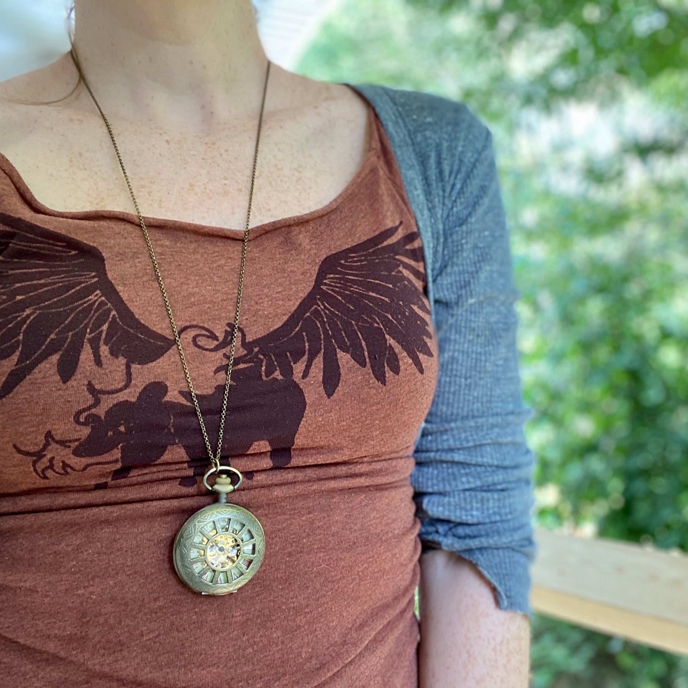 Antiqued brass mechanical watch with a cogwheel design on a necklace chain displayed on a model.