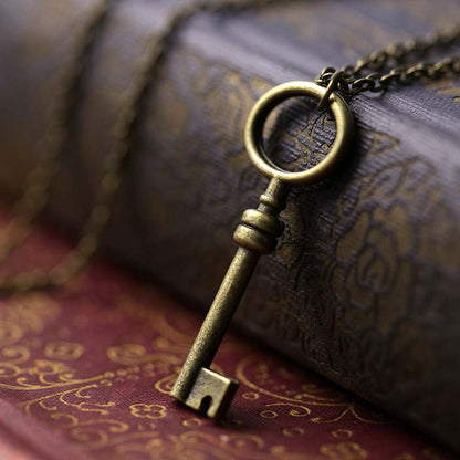Simple brass key with an oval head on a necklace chain.