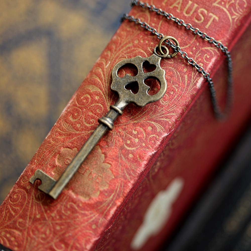 Antiqued brass key necklace. Head of the key has four cutouts, two of which are hearts.