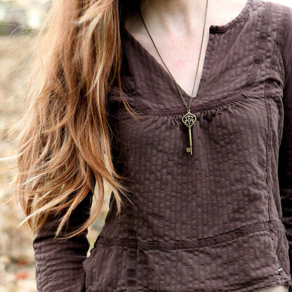 Antiqued brass key pendant necklace. Displayed on a model.