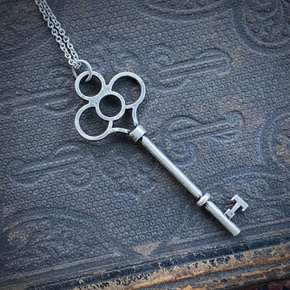 Antiqued silver key necklace with cutouts in the head of the key.