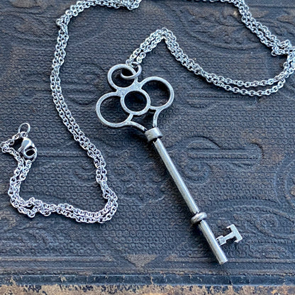 Antiqued silver key necklace with cutouts in the head of the key.