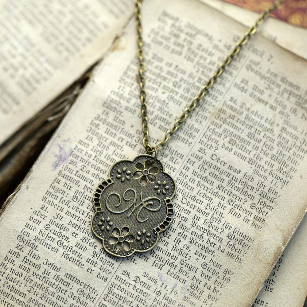Antique bronze letter M charm necklace with floral design.