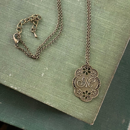 Antique bronze letter M charm necklace with floral design.
