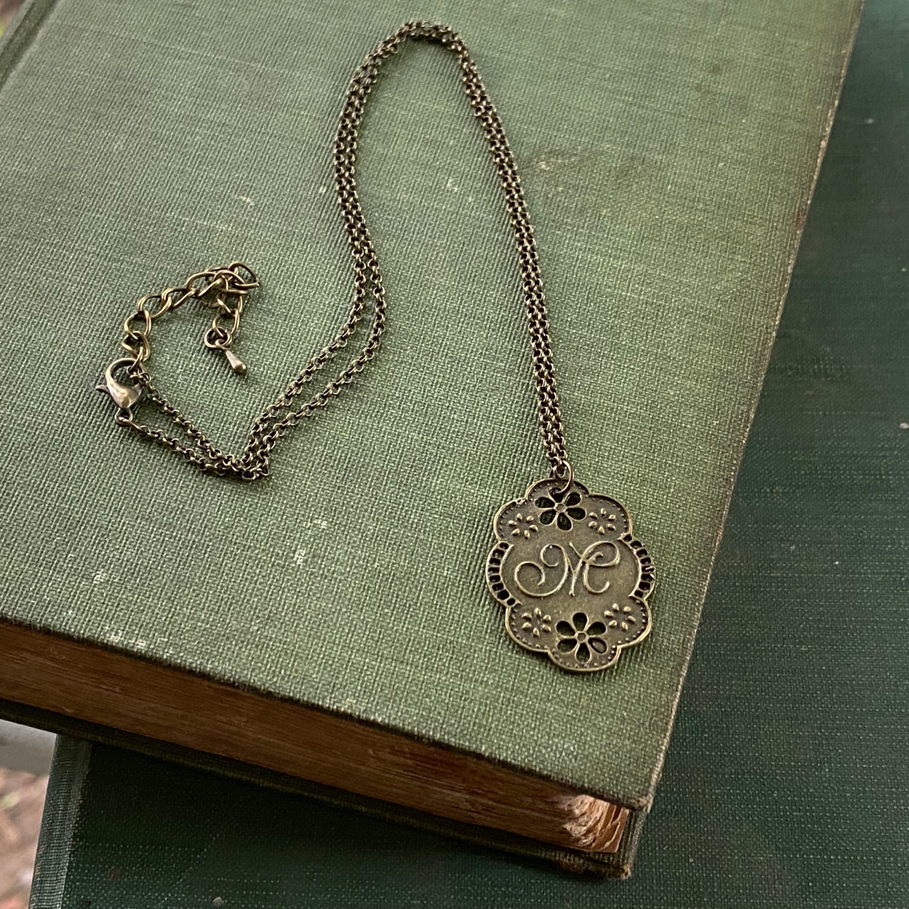 Antique bronze letter M charm necklace with floral design.