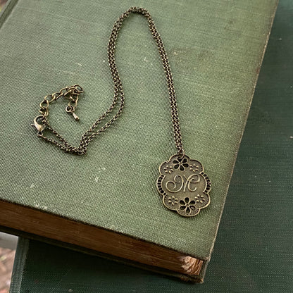 Antique bronze letter M charm necklace with floral design.