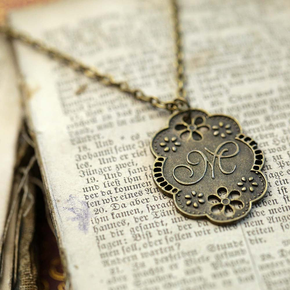 Antique bronze letter M charm necklace with floral design.