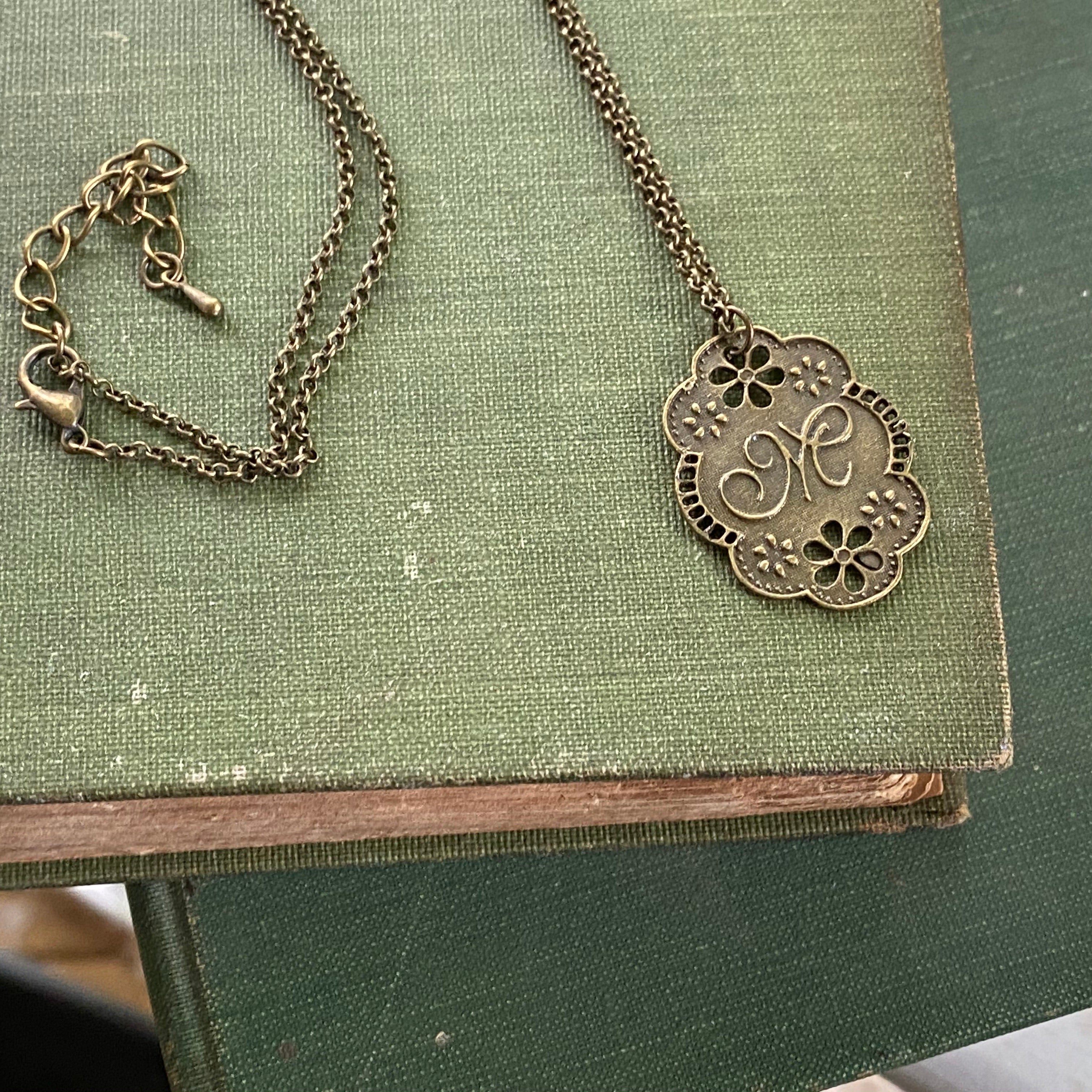 Antique bronze letter M charm necklace with floral design.