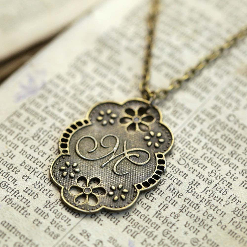 Antique bronze letter M charm necklace with floral design.