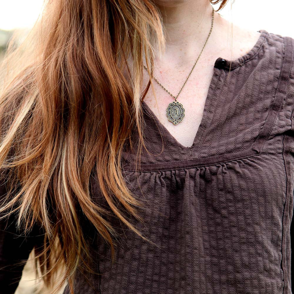 Antiqued brass letter 'A' pendant with an ornate border. The pendant is roughly oval shaped.