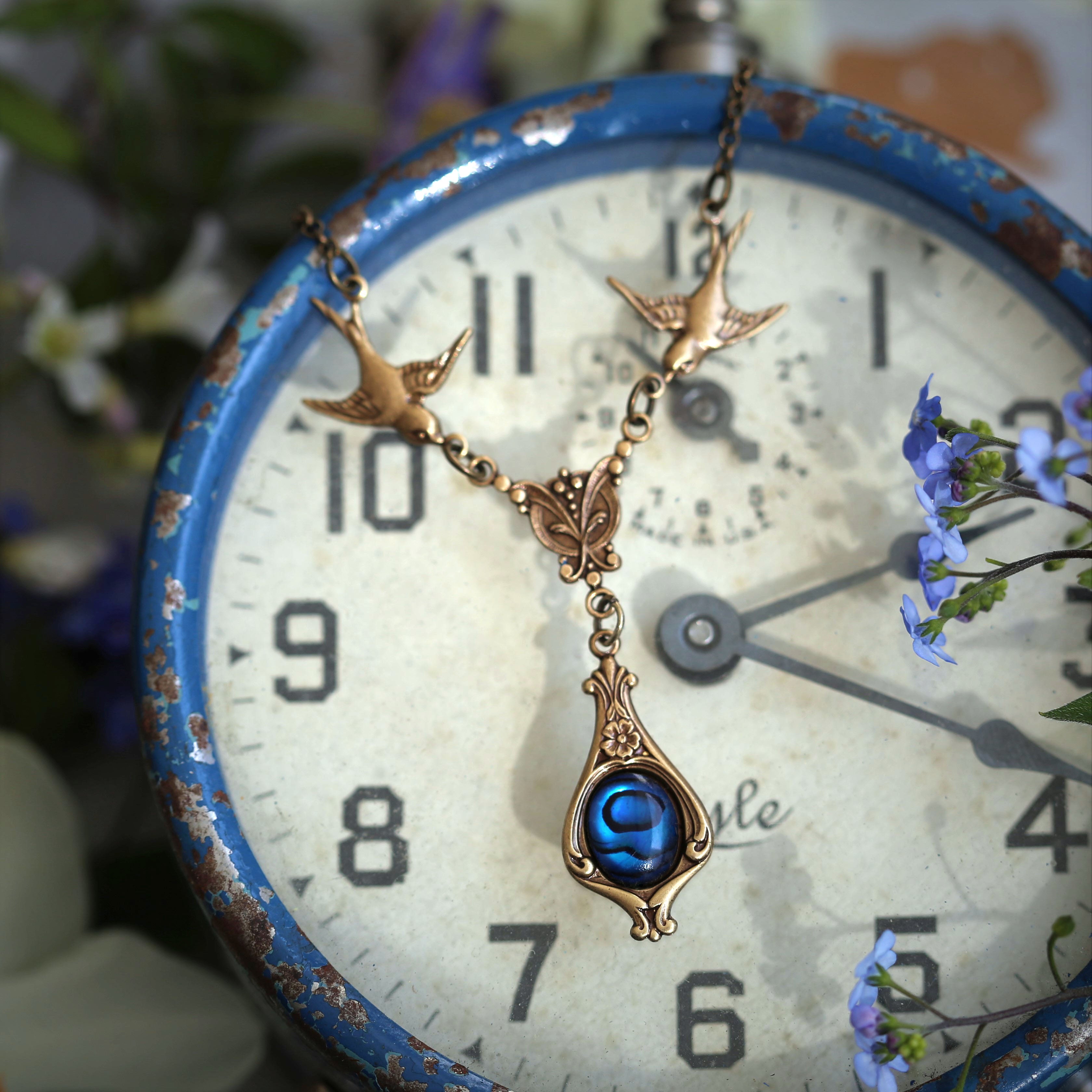 Antiqued brass vintage-style blue shell drop pendant featuring birds in a dark nautical style