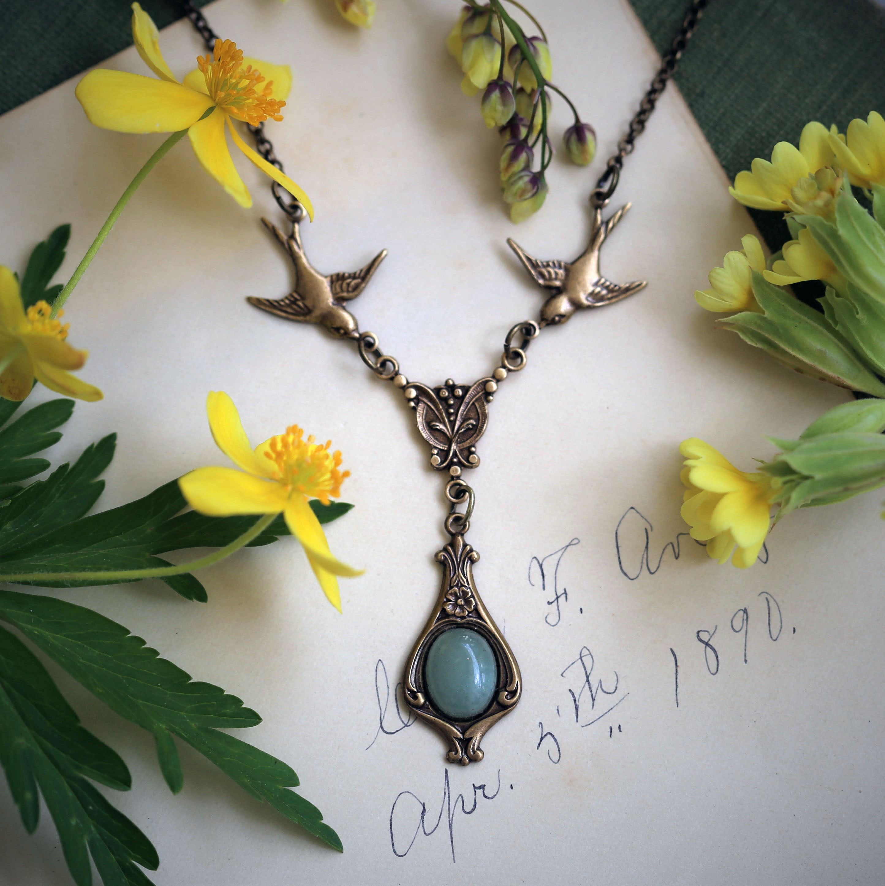 Antiqued brass vintage-style green aventurine drop pendant featuring birds in a cottagecore style.