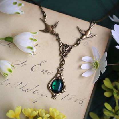 Antiqued brass vintage-style green shell drop pendant featuring birds in a winter green witch style.