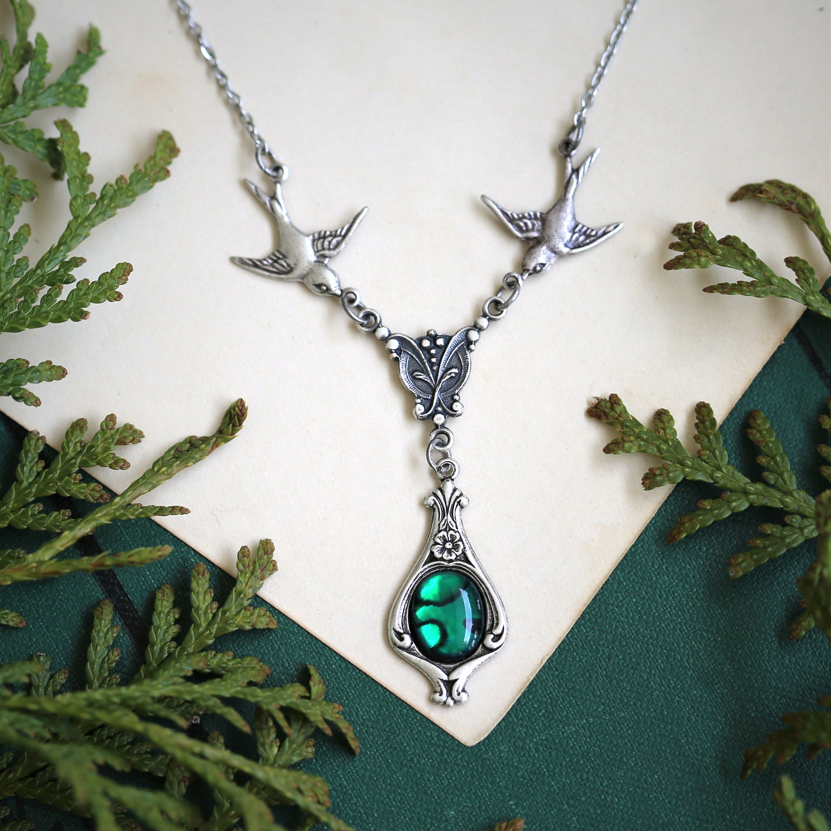 Antiqued silver vintage-style green shell drop pendant featuring birds in a light green goth style.