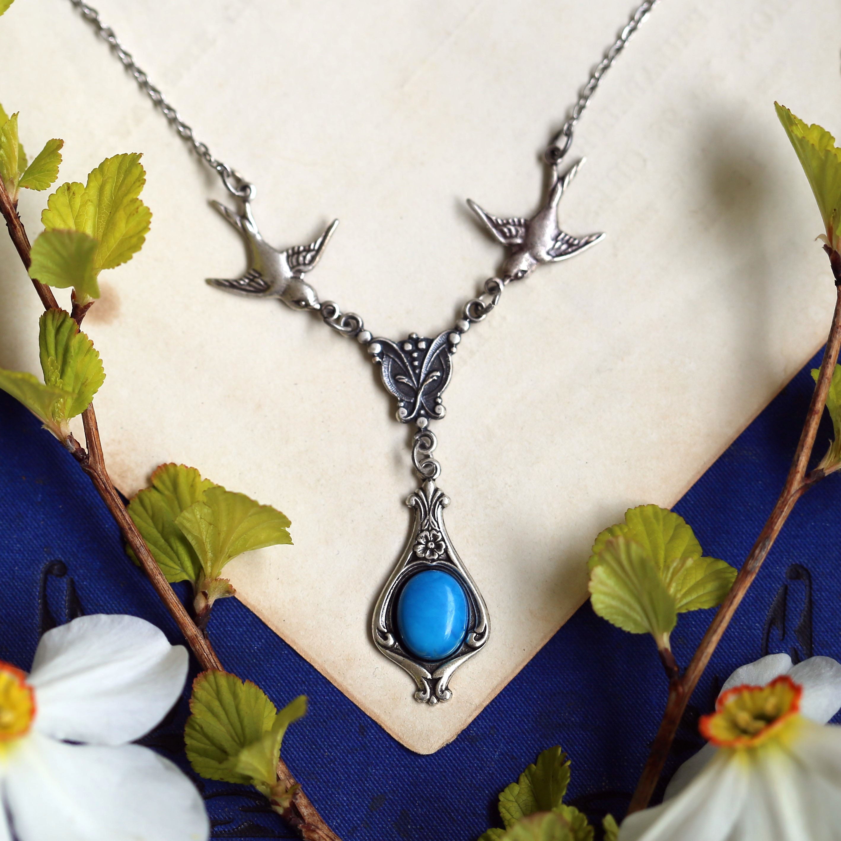 Antiqued silver vintage-style blue howlite drop pendant featuring birds in a boho style.