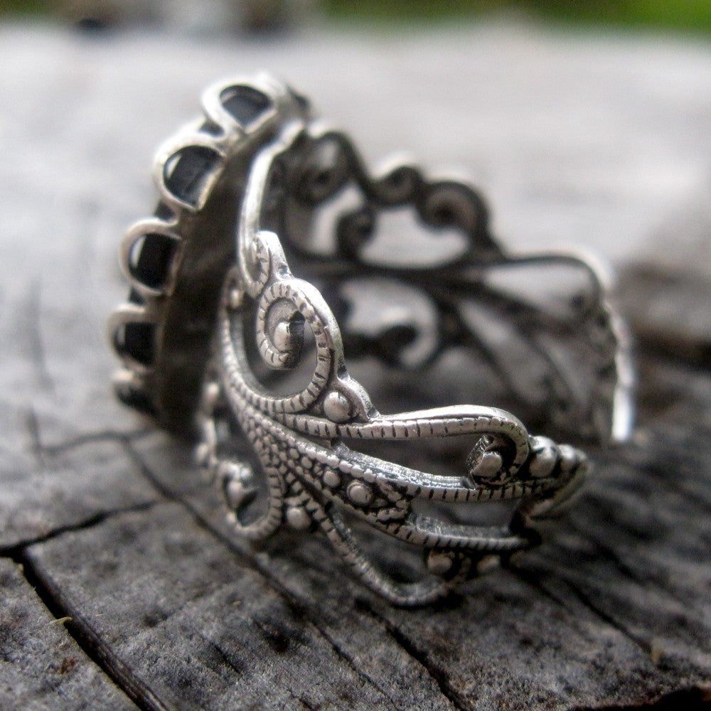 A cameo ring with a white woman on a black background. This oval cameo is set on an adjustable silver filigree ring.