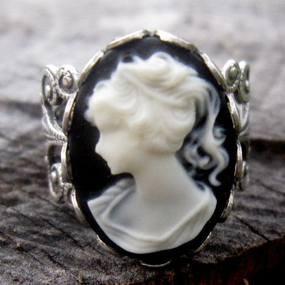 A cameo ring with a white woman on a black background. This oval cameo is set on an adjustable silver filigree ring.