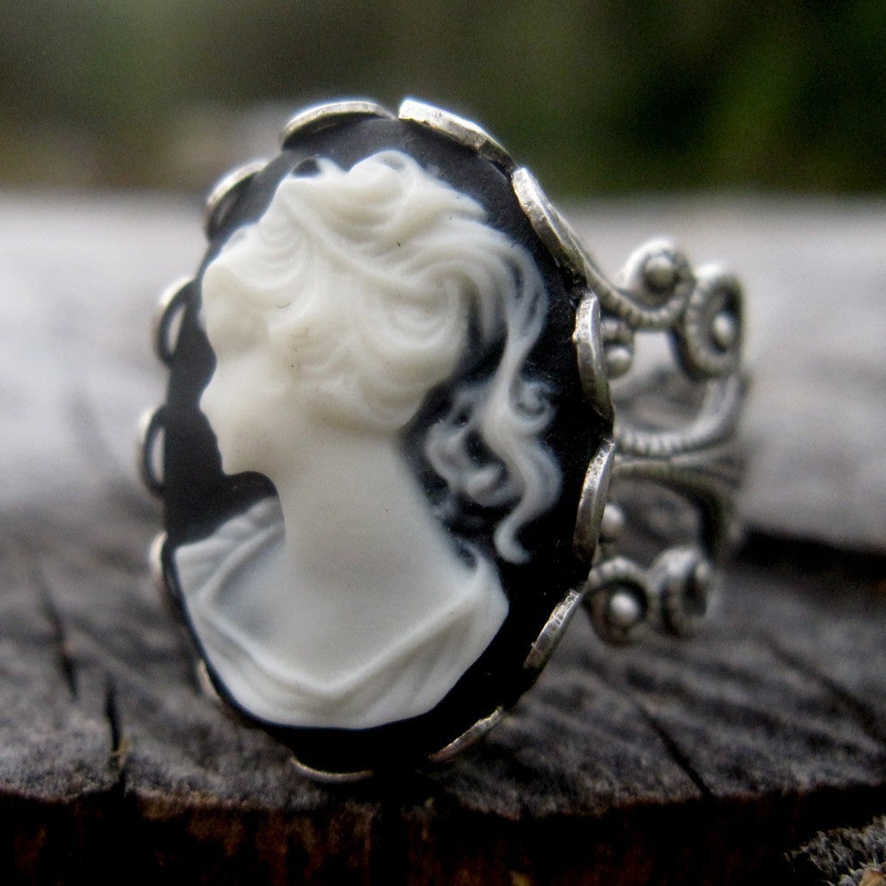 A cameo ring with a white woman on a black background. This oval cameo is set on an adjustable silver filigree ring.