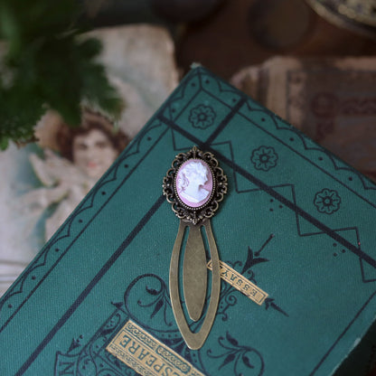 antiqued brass modern vintage inspired oval cameo clip bookmark with pink background and white lady profile cameo a perfect gift for book clubs.