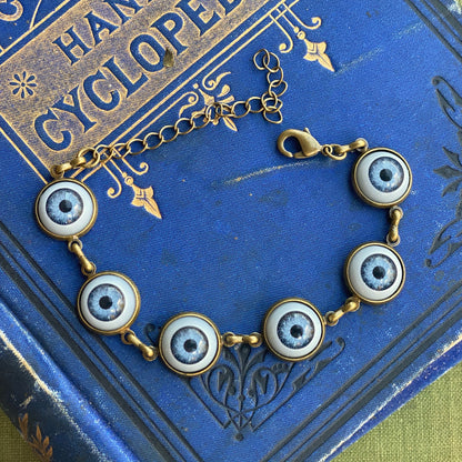 antiqued brass chaotic academia style adjustable blue evil eye charm dangle bracelet.