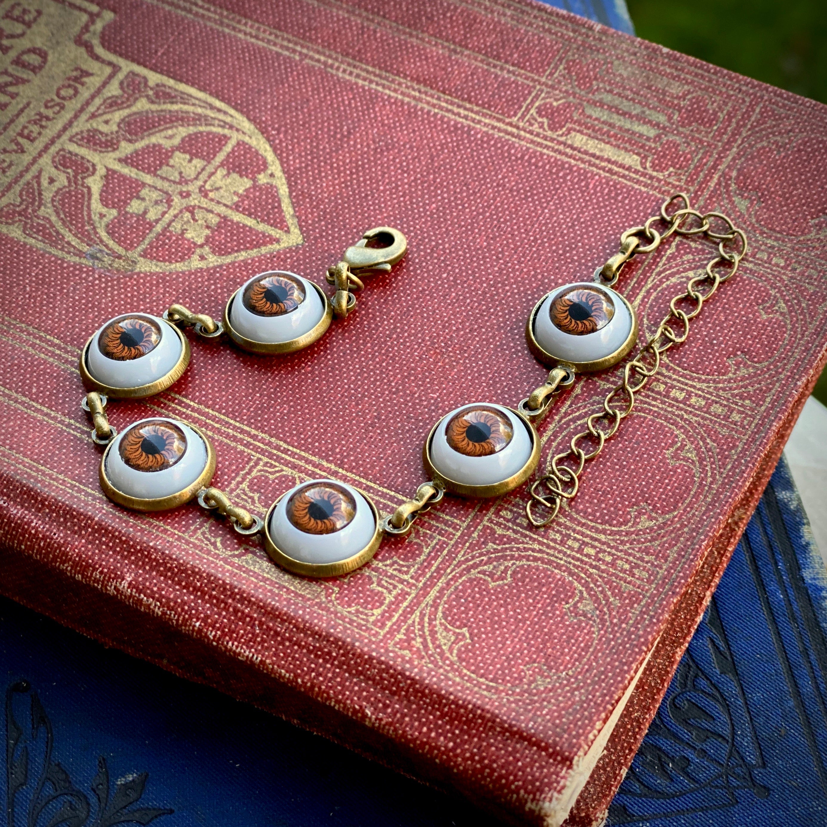 antiqued brass goblin academia style adjustable brown evil dolls eye charm dangle bracelet.