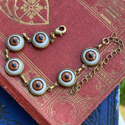 antiqued brass dark cottage core style adjustable brown evil eye charm dangle bracelet.