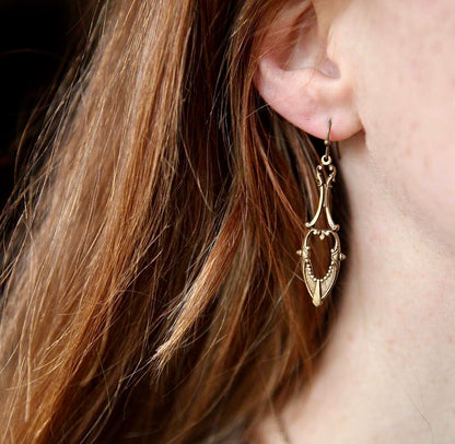 Antiqued brass drop earrings with a art deco cutout design.