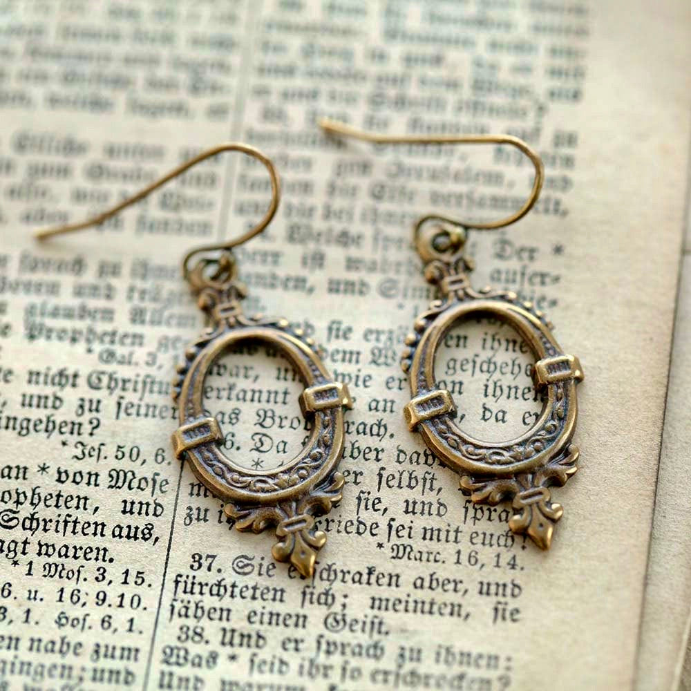 Antiqued brass drop earrings with a round cutout design.
