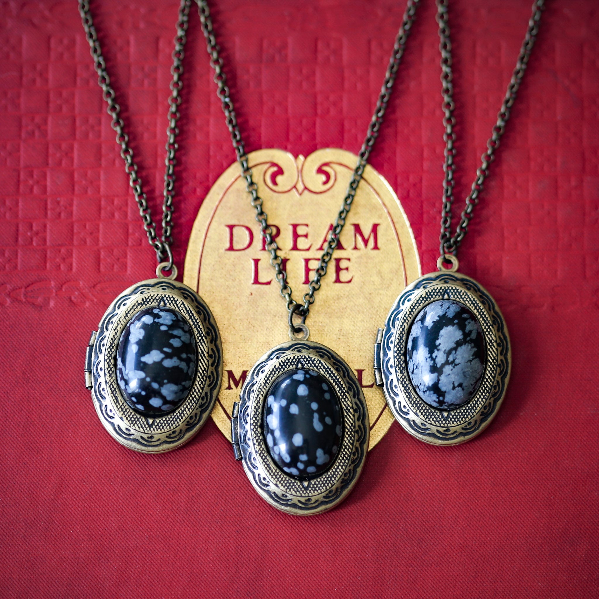 antiqued brass art academia snowflake obsidian gray and black semi-precious oval stone set on a locket making a great thoughtful gift for loved one.