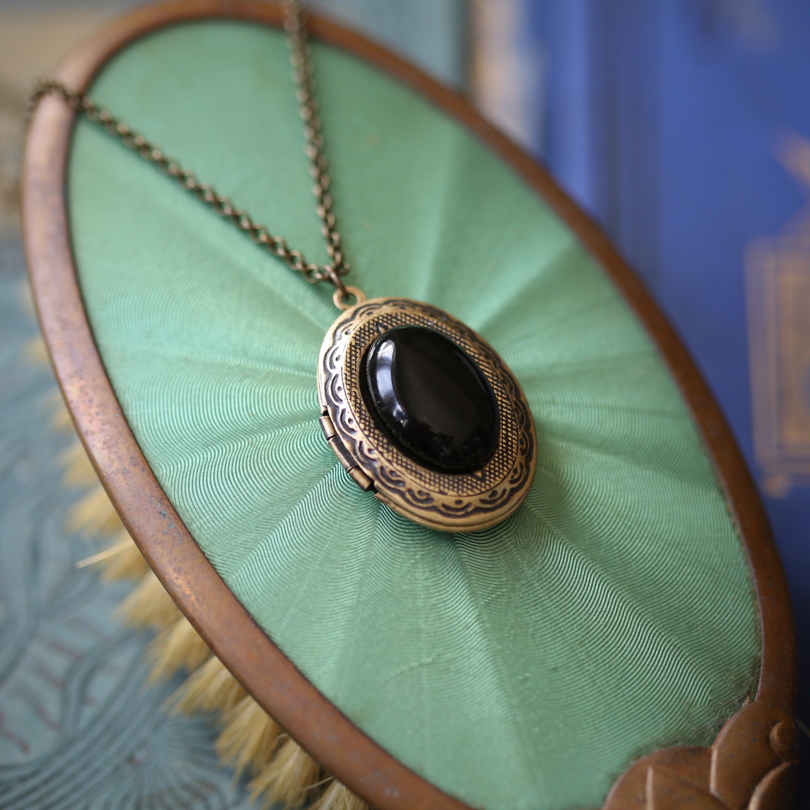 antiqued brass dark academia black onyx semi-precious oval stone set on a locket making a great thoughtful gift for loved one.